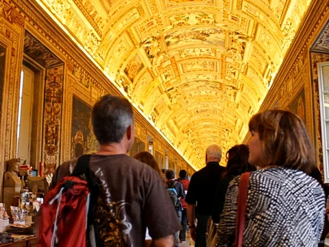Small group walking under the gilded vaulted ceiling of the Gallery of Maps on a Vatican pass ticket tour
